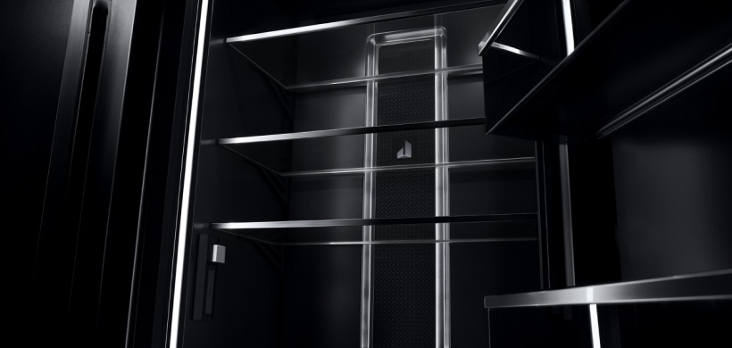 An opened JennAir Refrigerator. There are no contents but the shelves, including those on the door, are visible